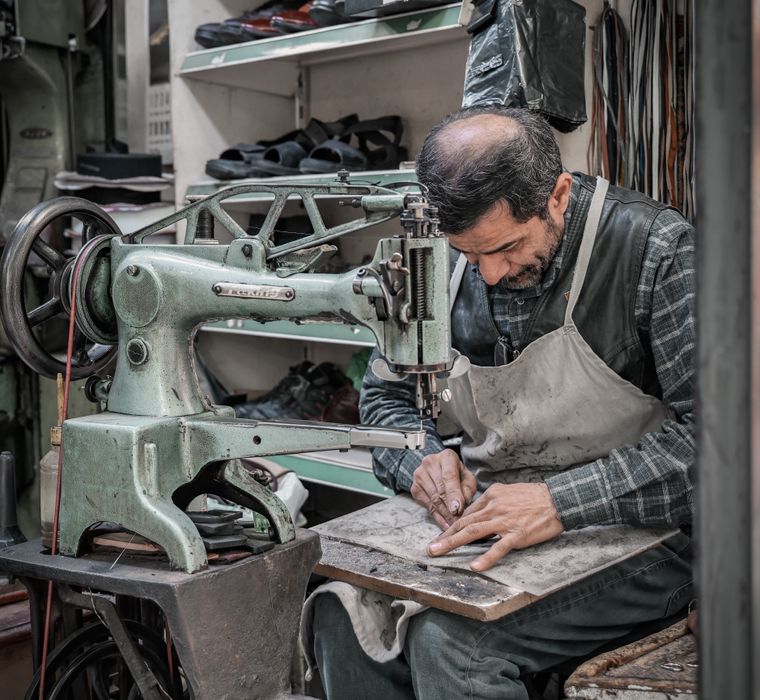 Un artisan au travail à sa machine, dans son atelier.