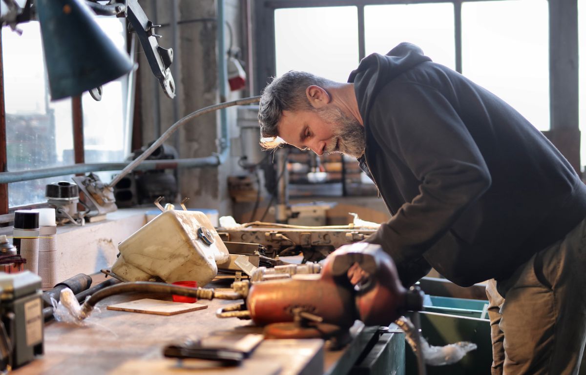 Un artisan penché sur son établi, dans la lumière de son atelier.