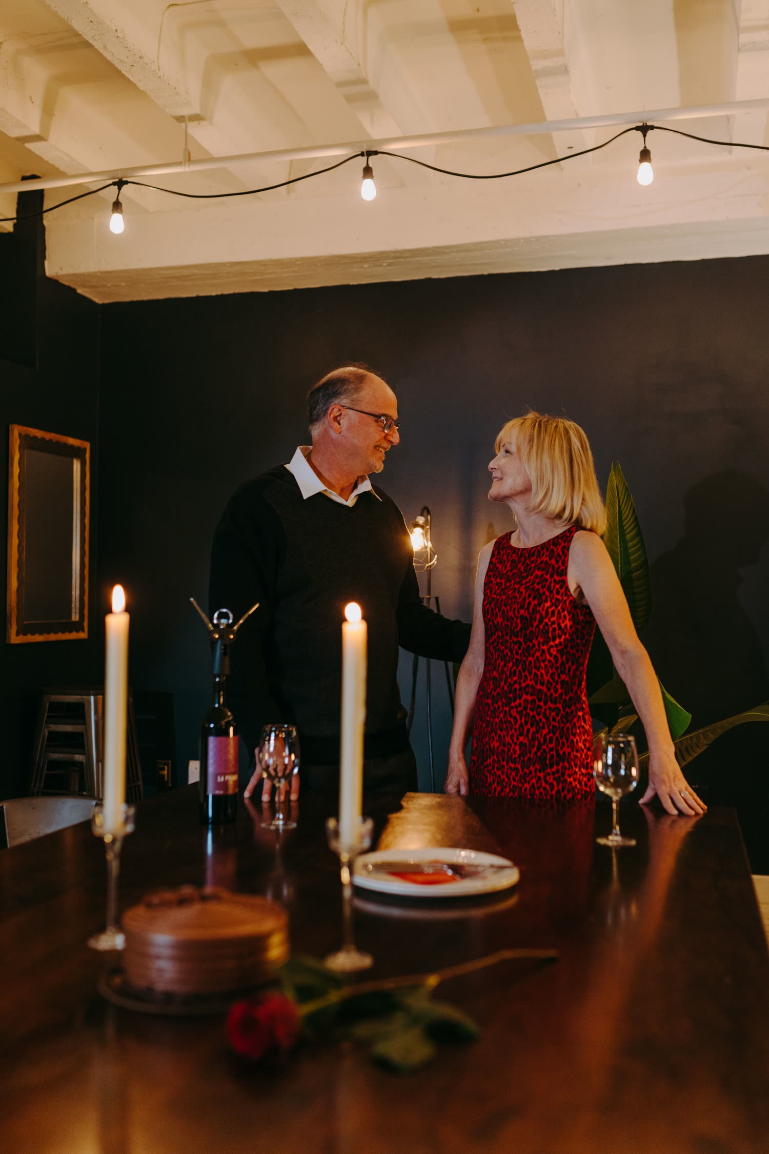 Un couple partage un souper aux chandelles, à la maison, en soirée.