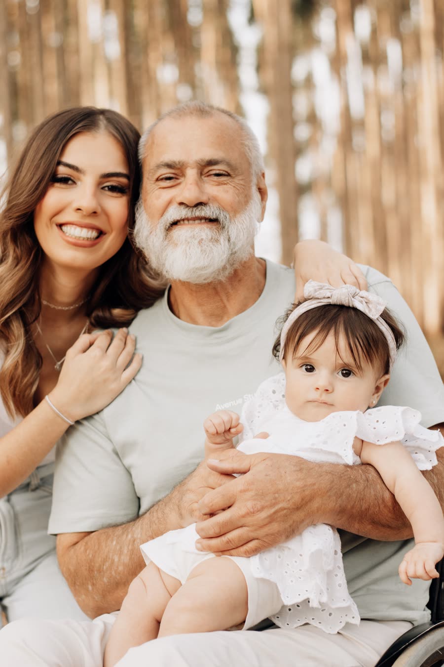 Un grand-père tient sa petite-fille dans ses bras, sa fille à ses côtés.