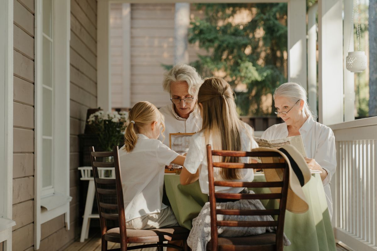 Une famille de trois générations réunie sur une véranda ensoleillée.